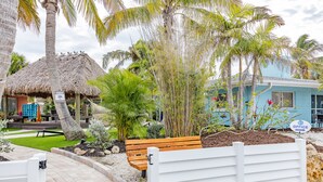 A tropical resort with a thatched-roof hut, a wooden bench, and a white fence. - Siesta Key Beachside Villas (Siesta Key)