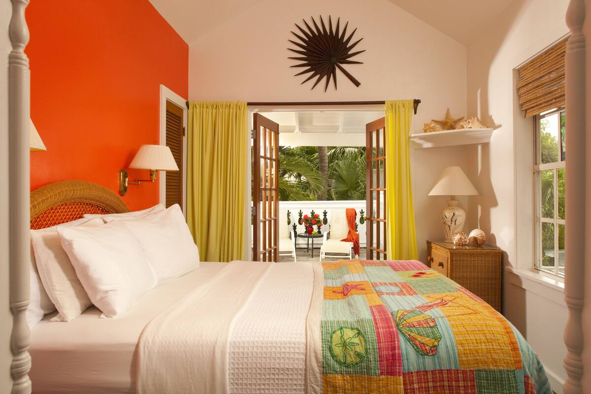 A bedroom with a bed, a nightstand, a window, and a view of the outdoors.