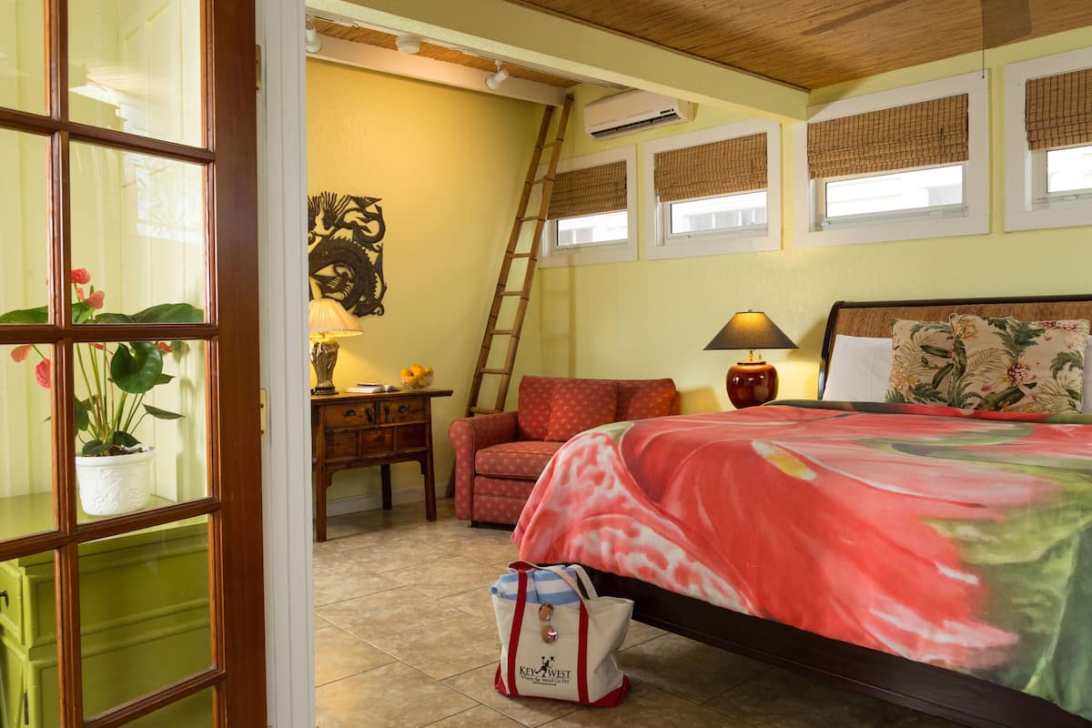 A bedroom with a bed, a chair, a desk, a lamp, and a window with blinds.