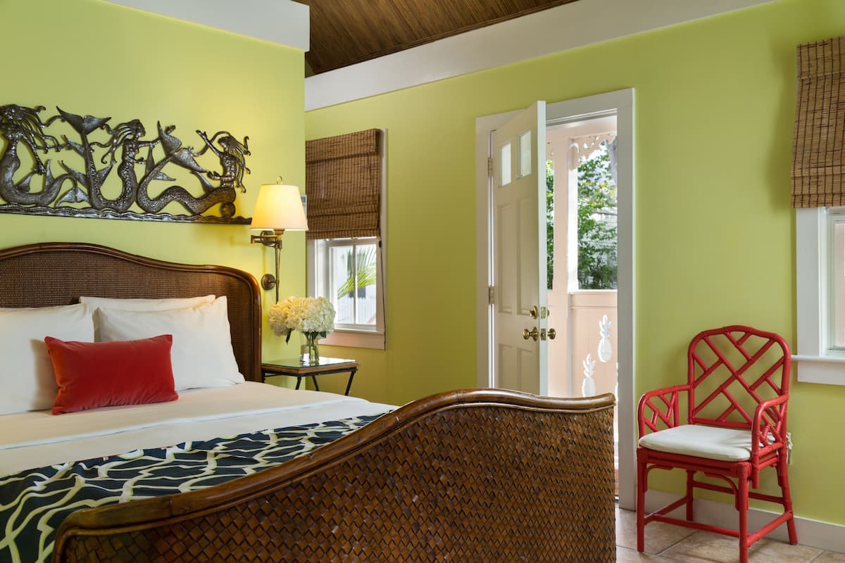 A bedroom with a bed, a red chair, and a decorative wall piece.