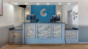 A reception desk with a stone facade, two chairs, and a large illuminated 'C' logo on the wall.