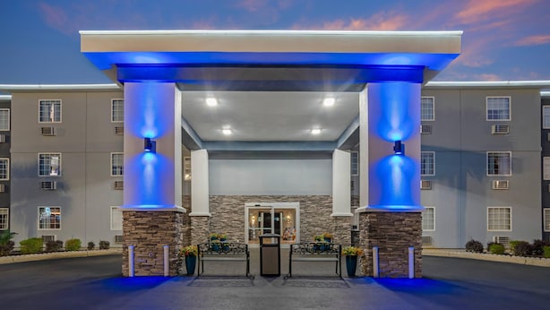 A hotel entrance with a stone facade, blue lighting on columns, and a clear sky.