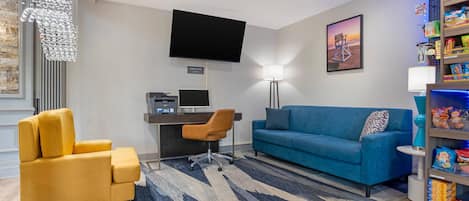 Un salon moderne comprenant un canapé, un fauteuil, un bureau et un téléviseur à écran plat.