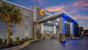 A hotel with a modern design, featuring a prominent 'Comfort Inn' sign, a covered entrance, and a parking area.