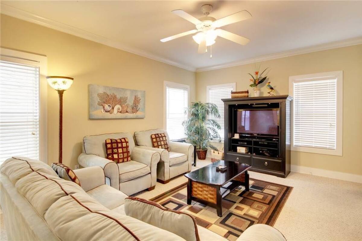 A living room with a ceiling fan, two couches, a coffee table, a TV, and a fireplace.