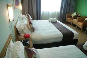 A hotel room with two beds, a sitting area with a chair, a small table with a vase of flowers, and a telephone on the nightstand. - Tang Dynasty Park Hotel (Kota Kinabalu)