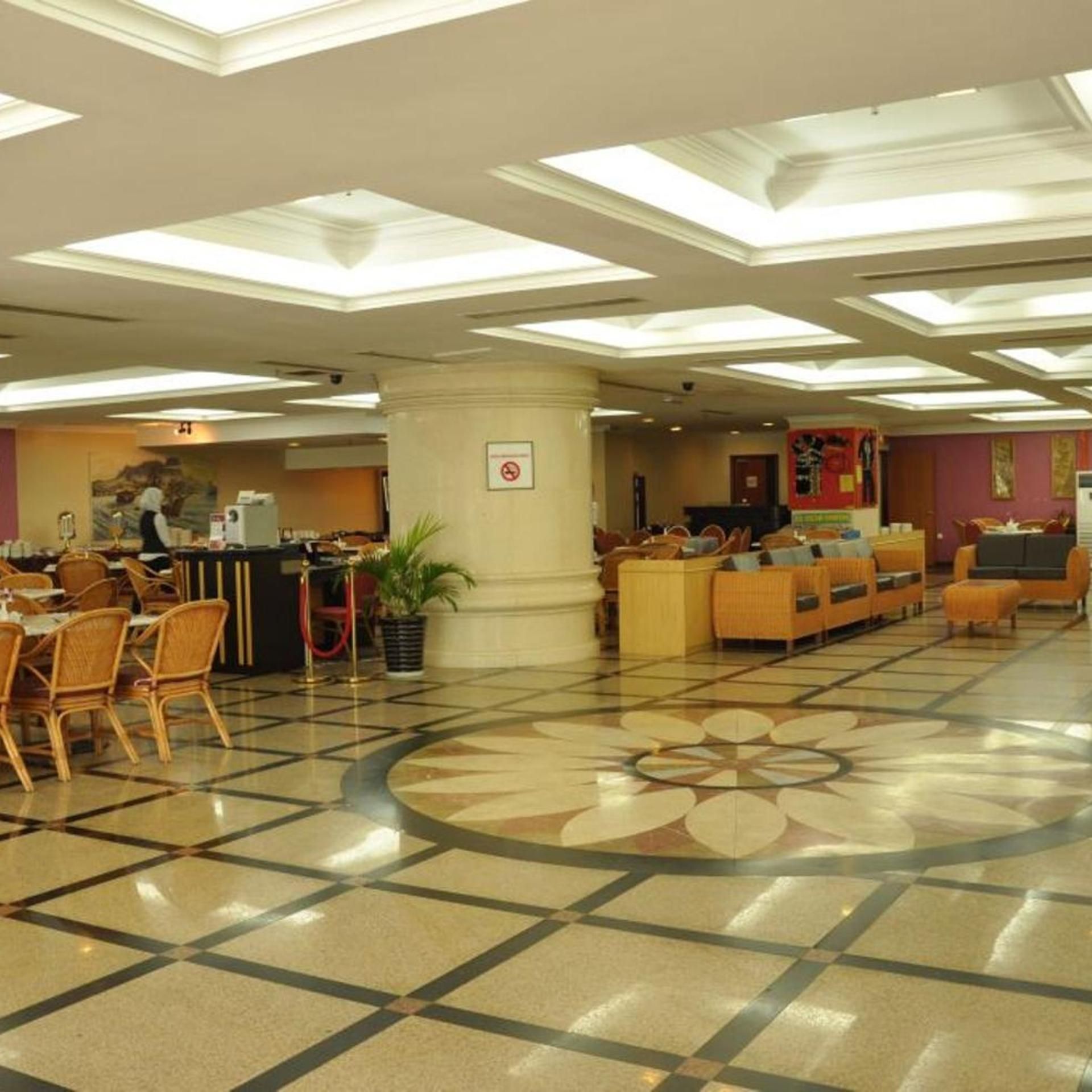 A hotel lobby with a check-in counter, seating area, and a patterned floor.