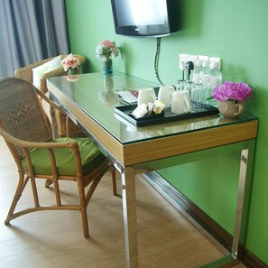 A hotel room with a glass-top table, wicker chair, green walls, and a flat-screen TV mounted on the wall. - Tang Dynasty Park Hotel (Kota Kinabalu)