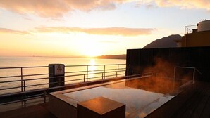 Una terraza con un jacuzzi, un letrero de advertencia y vistas del atardecer sobre el agua.