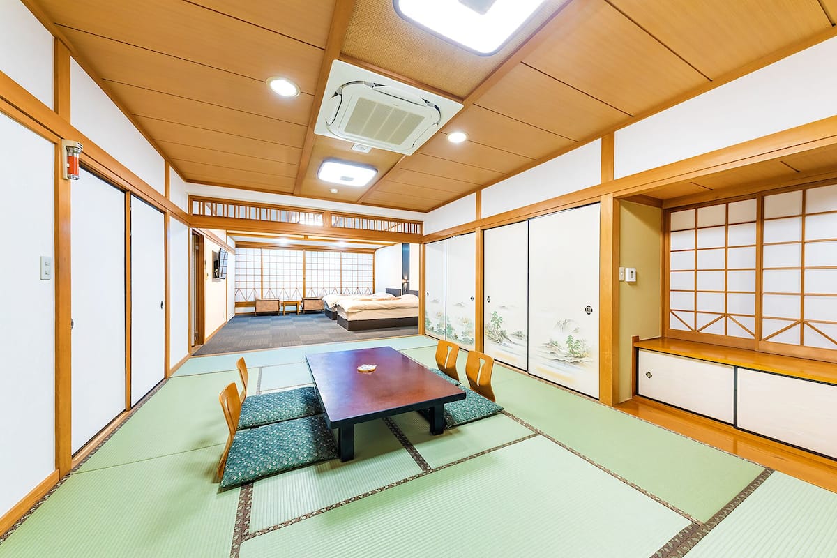 A traditional Japanese-style room with tatami flooring, a low table with cushions, and sliding shoji doors.