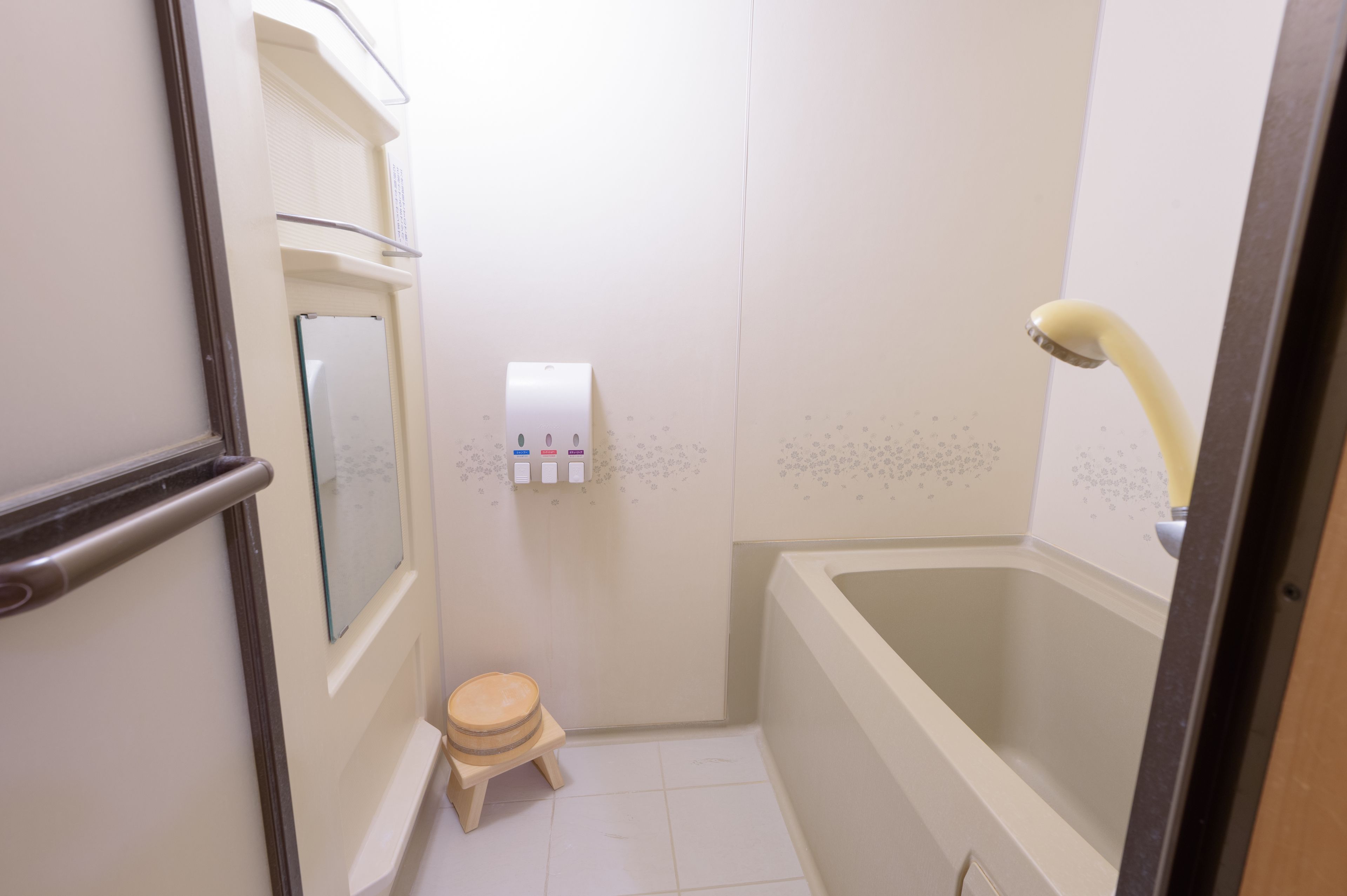A small bathroom with a bathtub, a toilet, and a hand sanitizer dispenser.