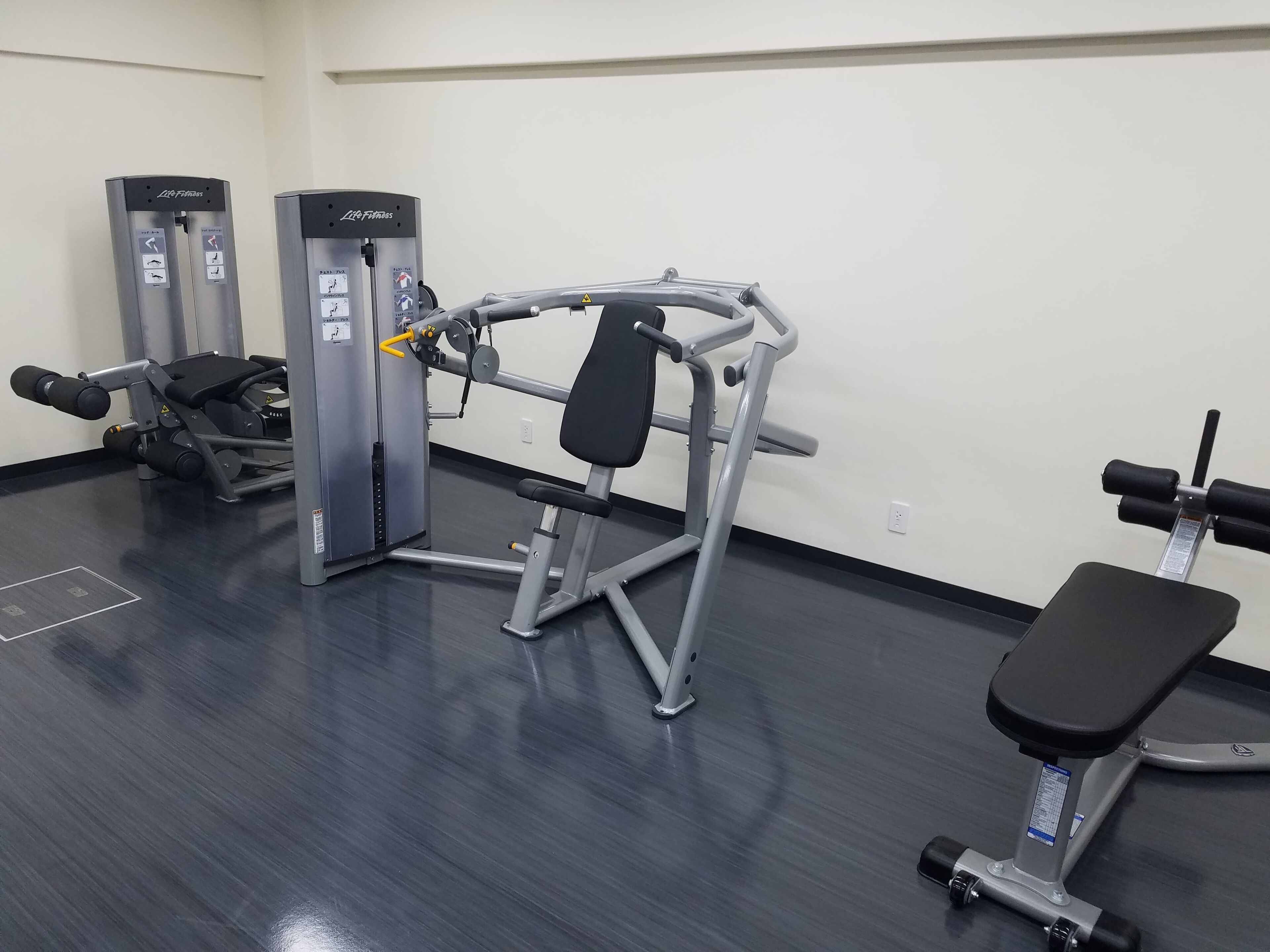 A gym with exercise equipment including a bench, weight machines, and a treadmill.