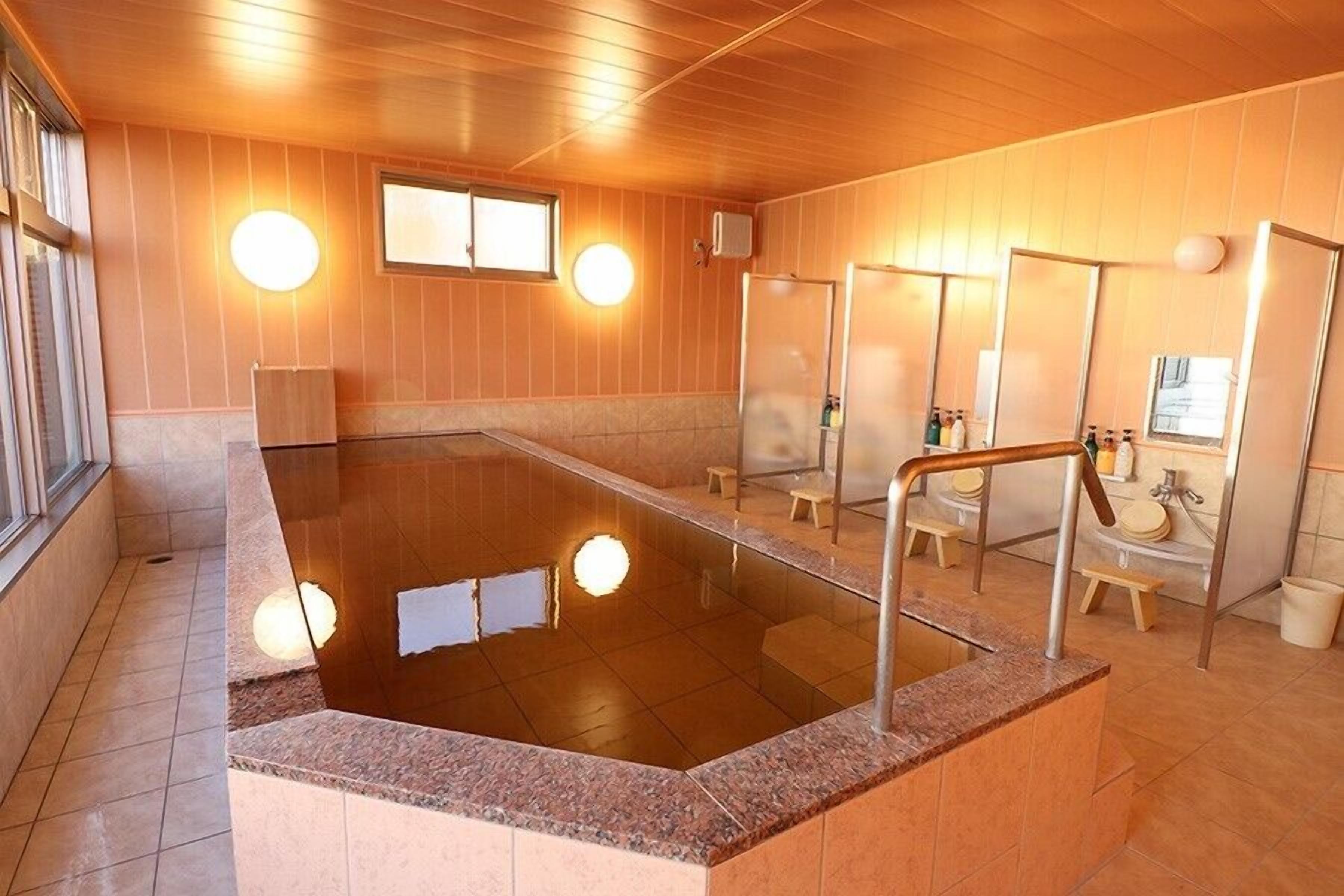 A traditional Japanese onsen with a hot spring, wooden walls, and a tiled floor.
