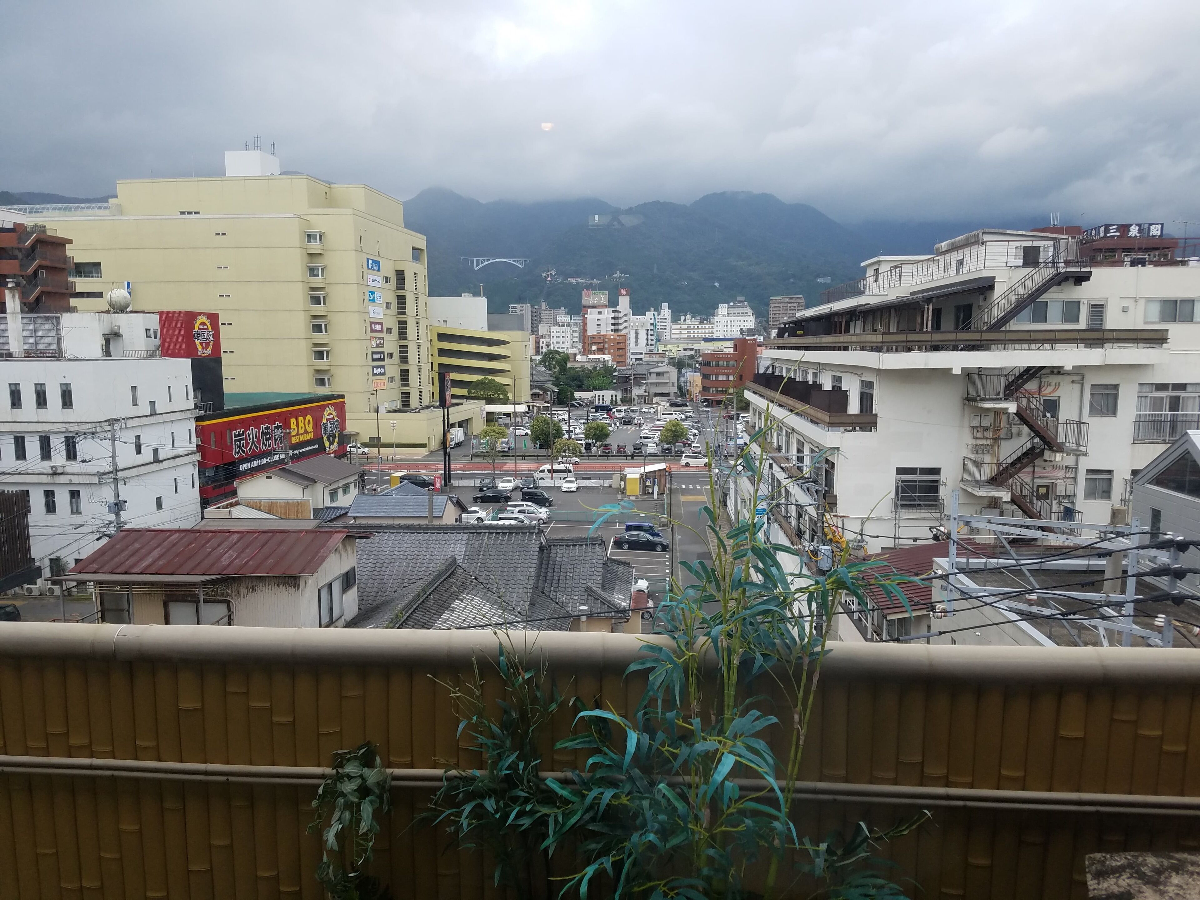 A cityscape with buildings, a road, and mountains in the background.