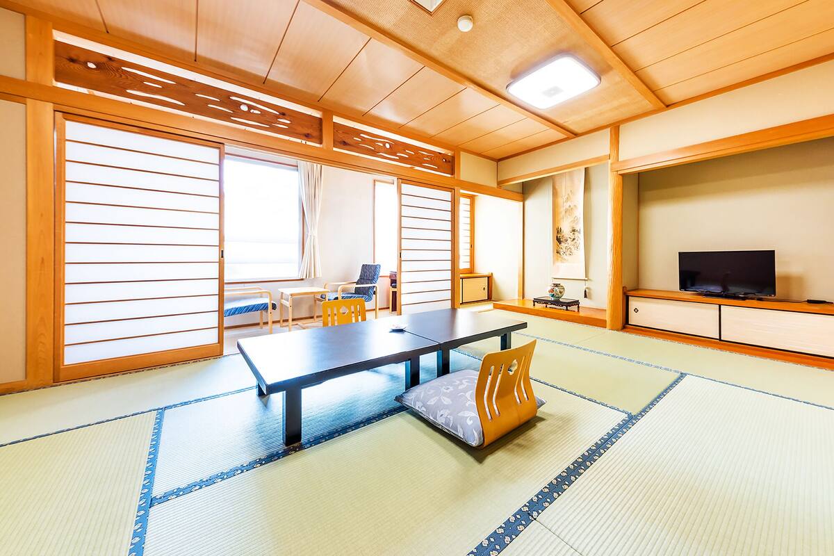 A traditional Japanese room with tatami flooring, a low table, and sliding doors.