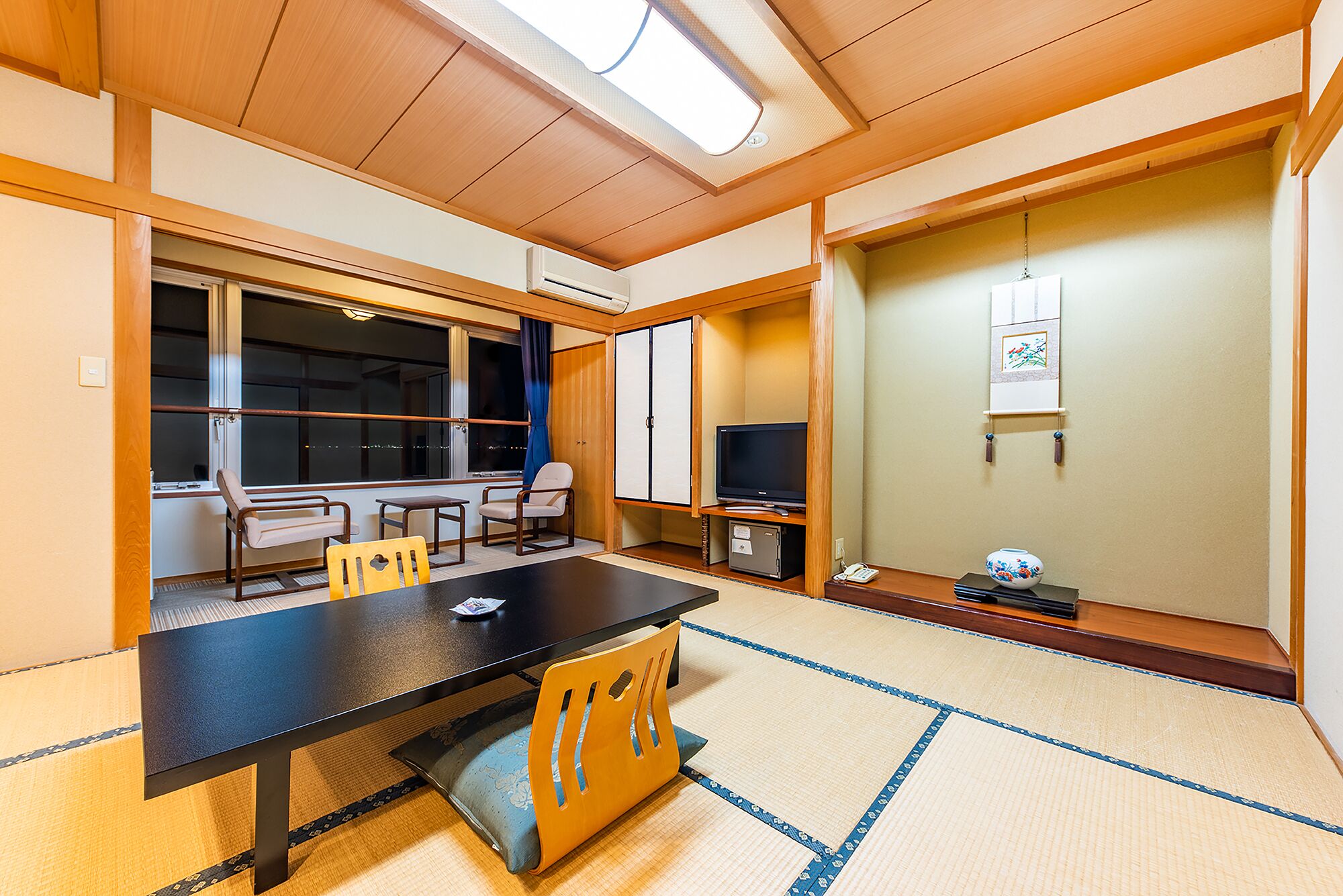 A traditional Japanese room with tatami flooring, a low table, and a television.