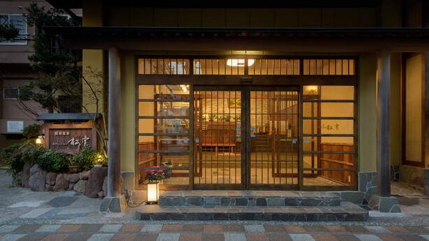 Un edificio japonés tradicional con una entrada de madera y escalones de piedra.
