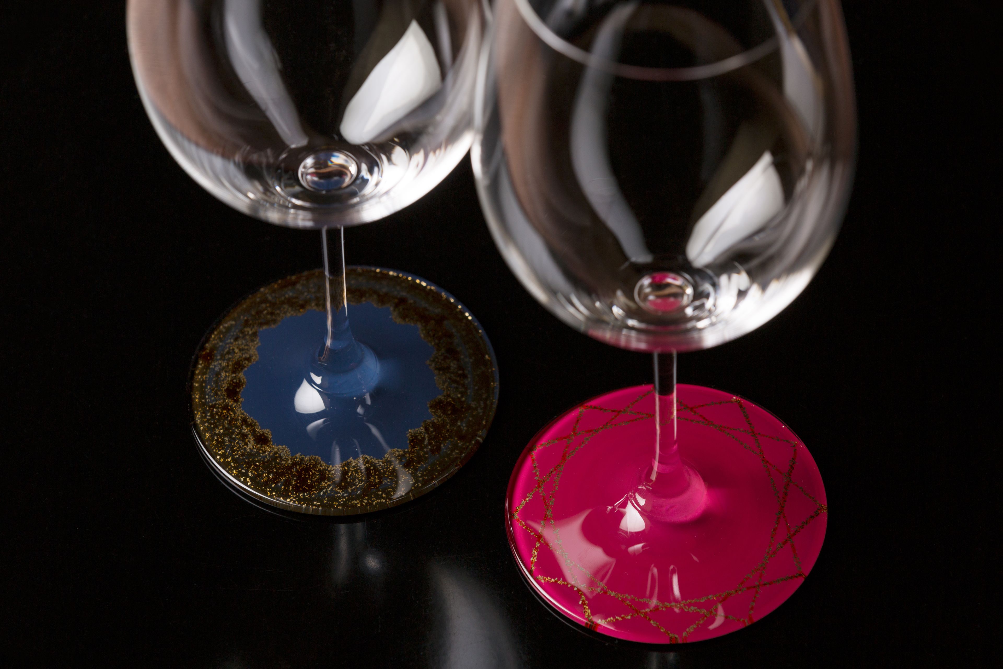 Two wine glasses with unique designs on their bases.