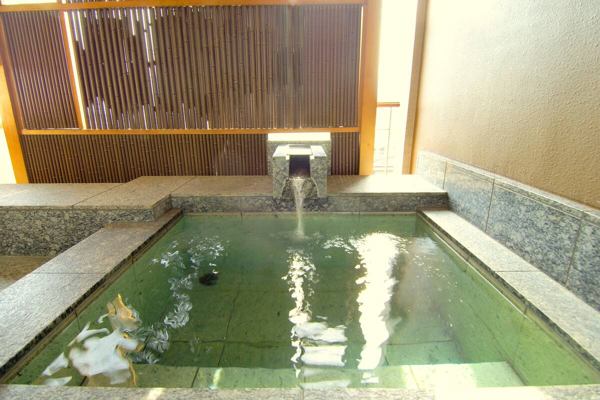 A rectangular pool with a small waterfall feature in the center, surrounded by stone steps and walls.