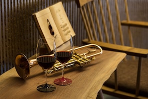 Une table en bois avec deux verres de vin rouge et une trompette en laiton.