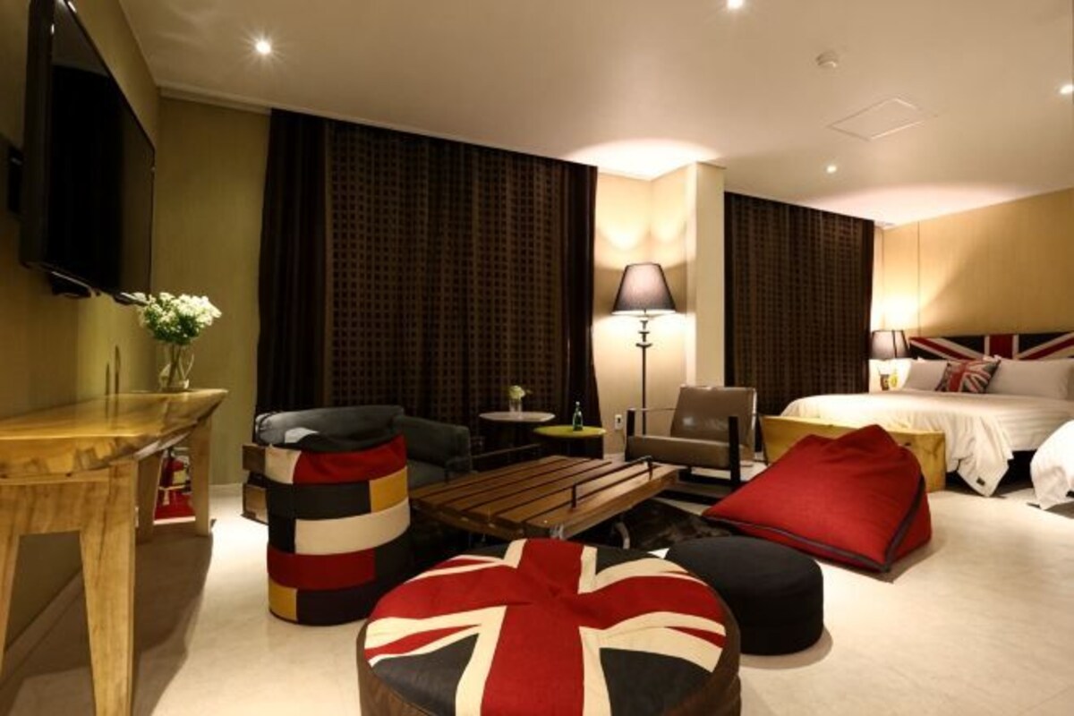 A hotel room with a bed, a sofa, a coffee table, a TV, and a lamp.
