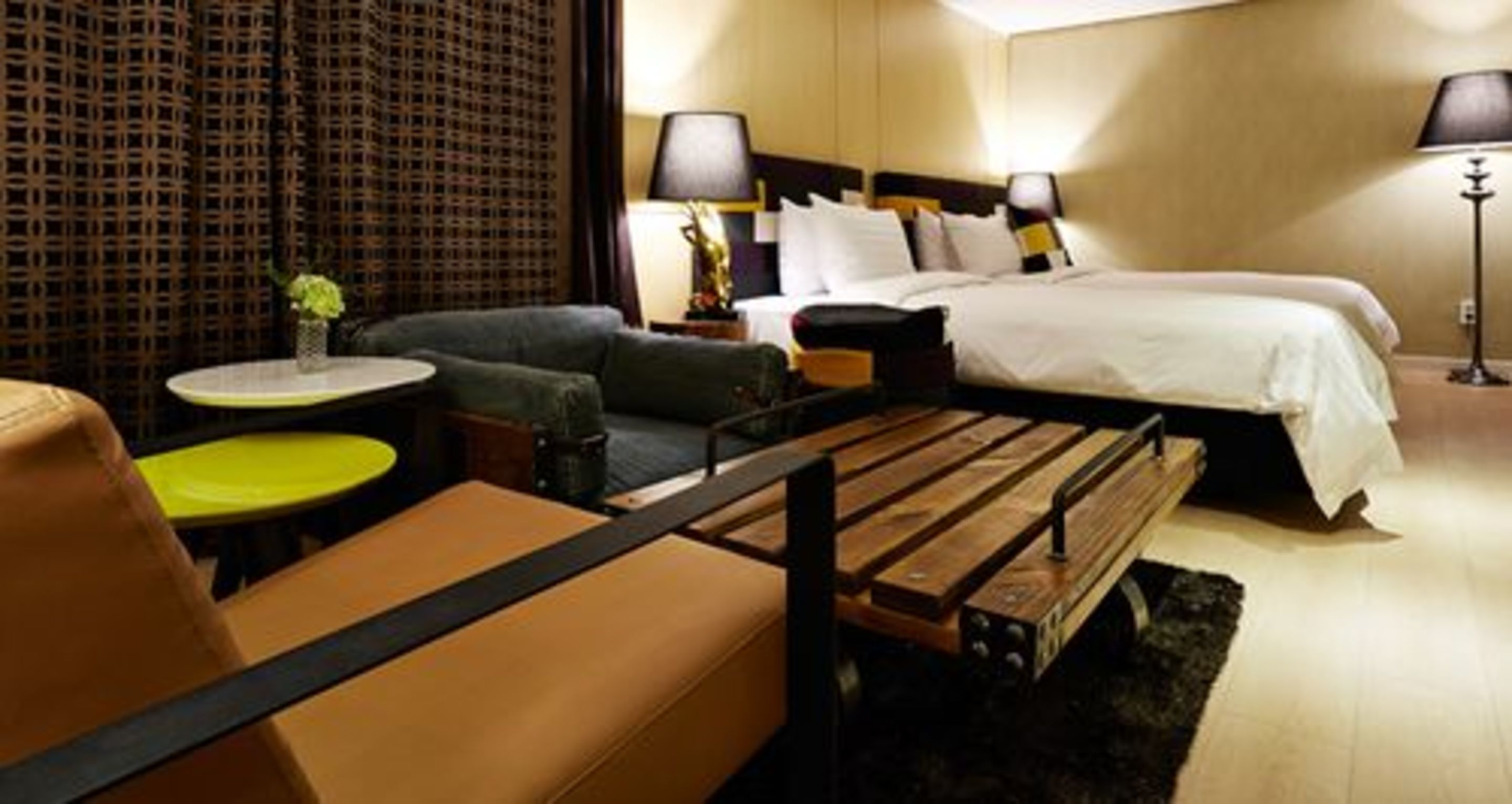 Une chambre d’hôtel avec un lit, un canapé, une petite table ronde et un banc.
