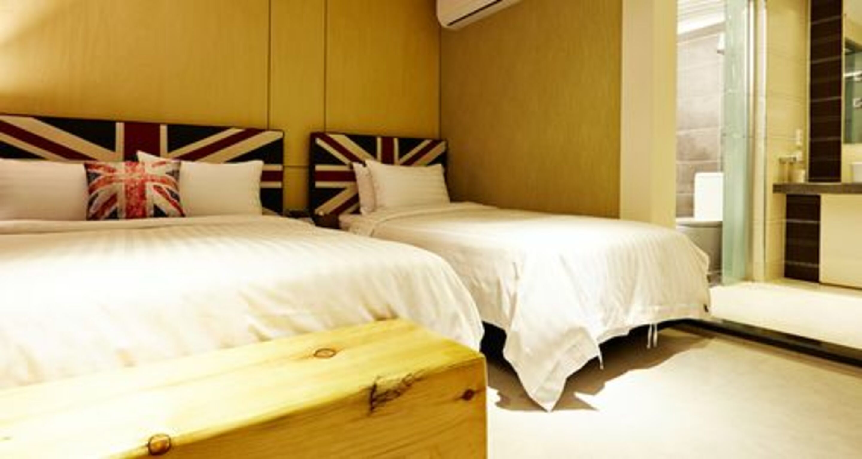 A hotel room with two beds, a wooden headboard, and a large window.