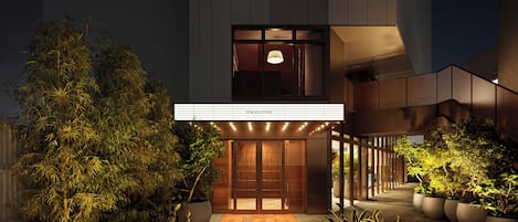 A hotel entrance with a modern design, featuring a prominent signboard and a pathway leading to the entrance.