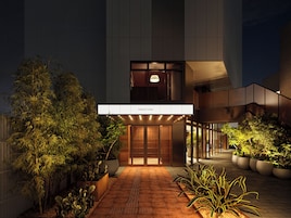 A hotel entrance with a modern design, featuring a prominent signboard and a pathway leading to the entrance.