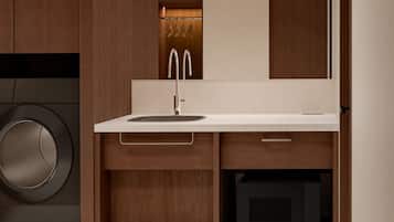 A modern bathroom with a built-in washing machine, a sink with a mirror, and wooden cabinetry.