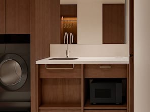 Un bagno moderno con lavatrice integrata, un lavandino con specchio e mobili contenitori in legno.