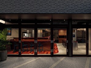 Un espace bar moderne, doté de sièges et d’une cuisine ouverte visible au fond.