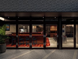 A modern bar area with seating and a visible kitchen in the background.