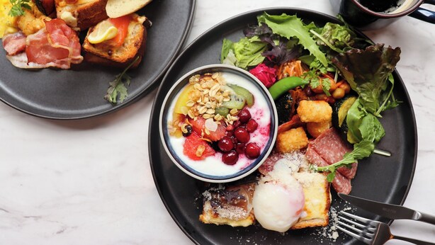A breakfast setting with plates of food, a bowl of yogurt with berries, and a cup of coffee. - Tokyu Stay Shinjuku (Tokyo)