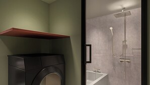 A modern bathroom with a built-in washer, a bathtub, and a shower. - Tokyu Stay Shinjuku (Tokyo)