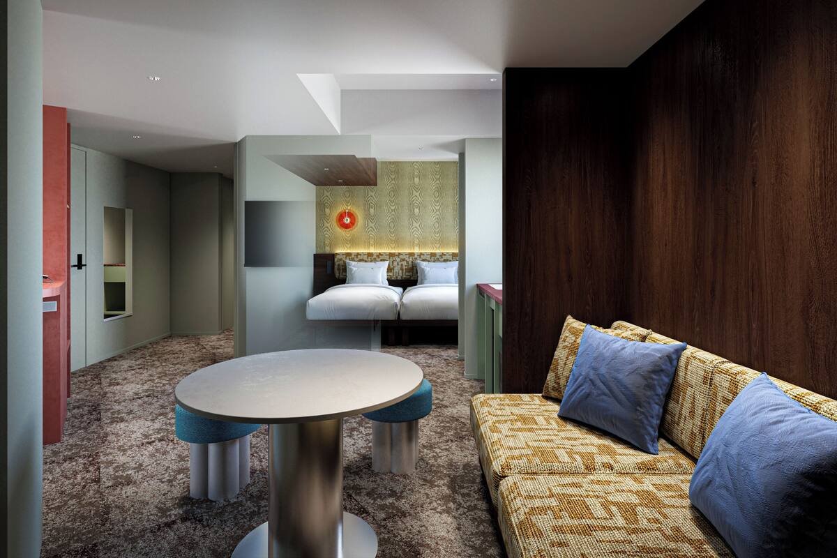 Una camera d'hotel moderna con un tavolino rotondo, una poltrona, un letto con lenzuola bianche e una parete decorativa in legno.