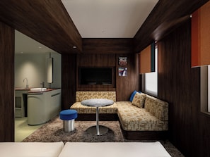 A compact room with a kitchenette, a sofa, a small table, and a TV mounted on the wall. - Tokyu Stay Shinjuku (Tokyo)
