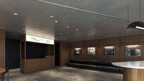 Un espace d’accueil moderne comprenant un comptoir d’accueil en bois, un coin salon et un mur orné de photographies encadrées.