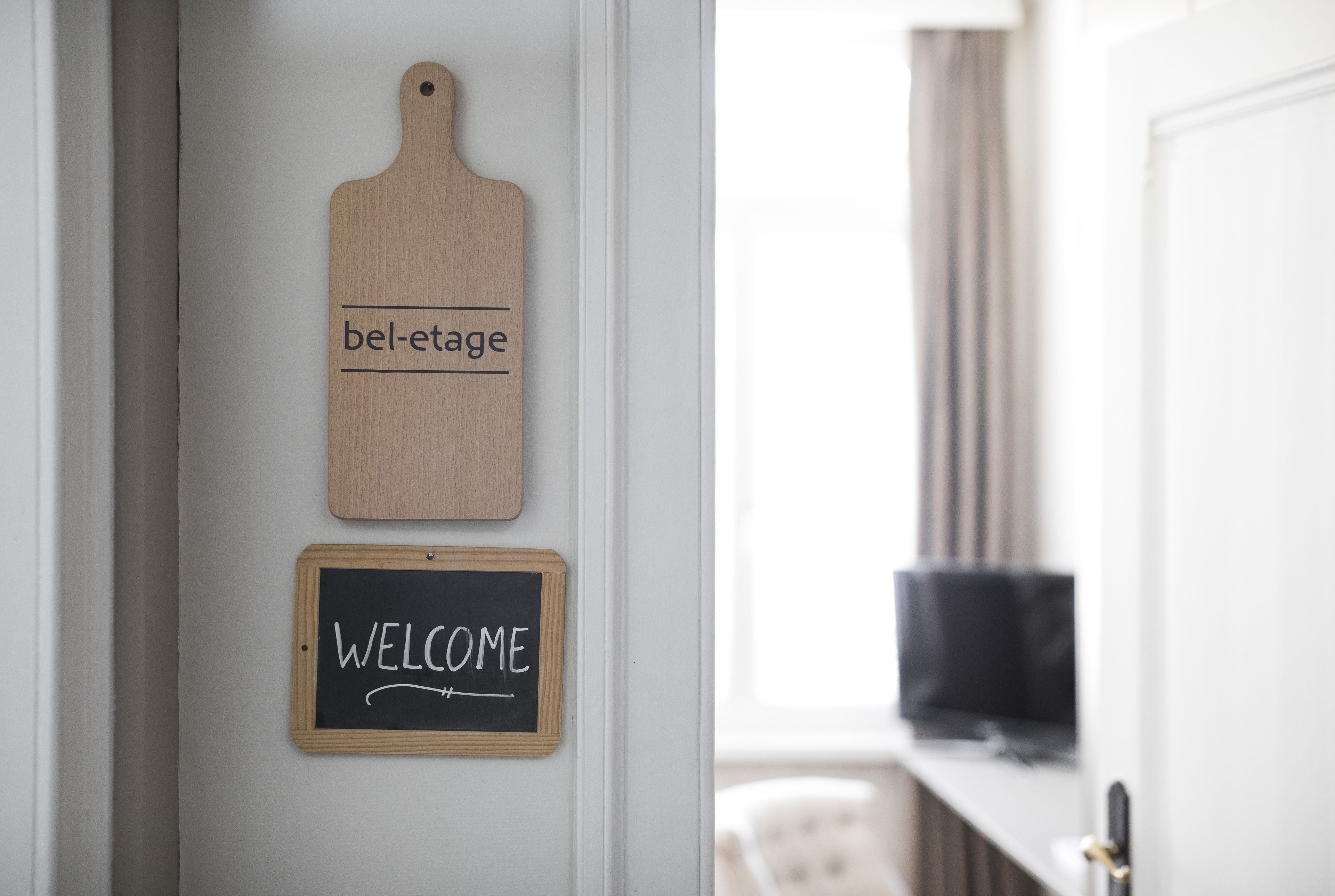 A wooden sign with "bel-etage" and a chalkboard with "WELCOME" on a door.