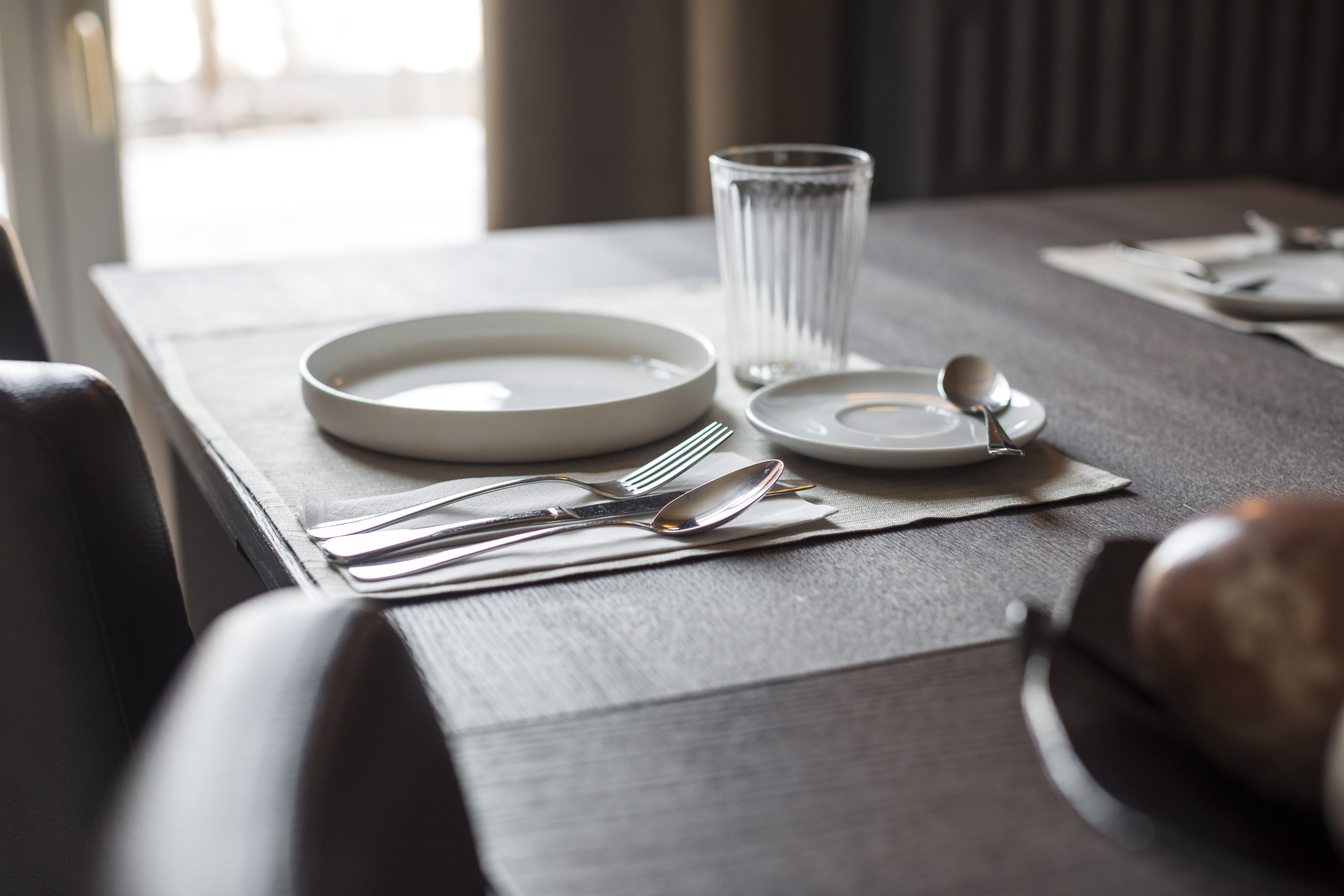 A neatly set dining table with plates, cutlery, and a glass.