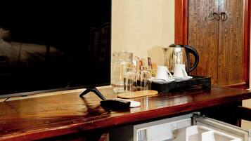 A compact kitchen with a refrigerator, a coffee maker, and a television.