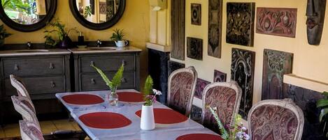 A dining area with a long table, ornate chairs, and decorative wall art.