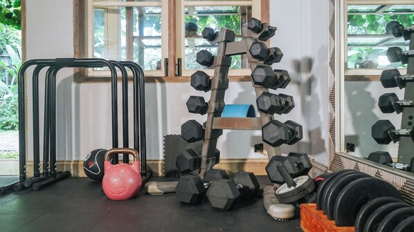 Une salle de sport équipée de matériel de musculation, notamment des haltères et un kettlebell.