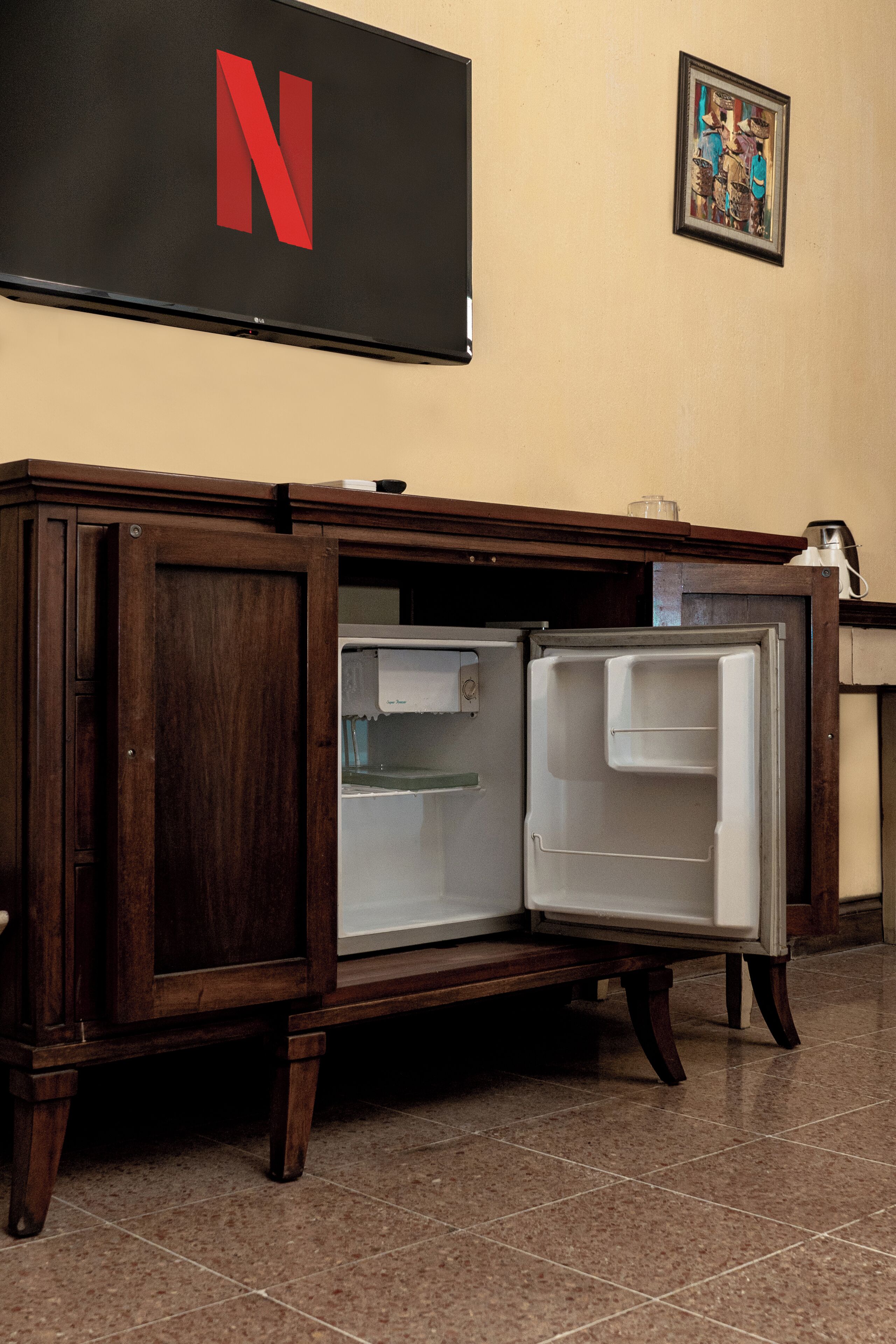 A wooden cabinet with a large Netflix logo on the wall above it.