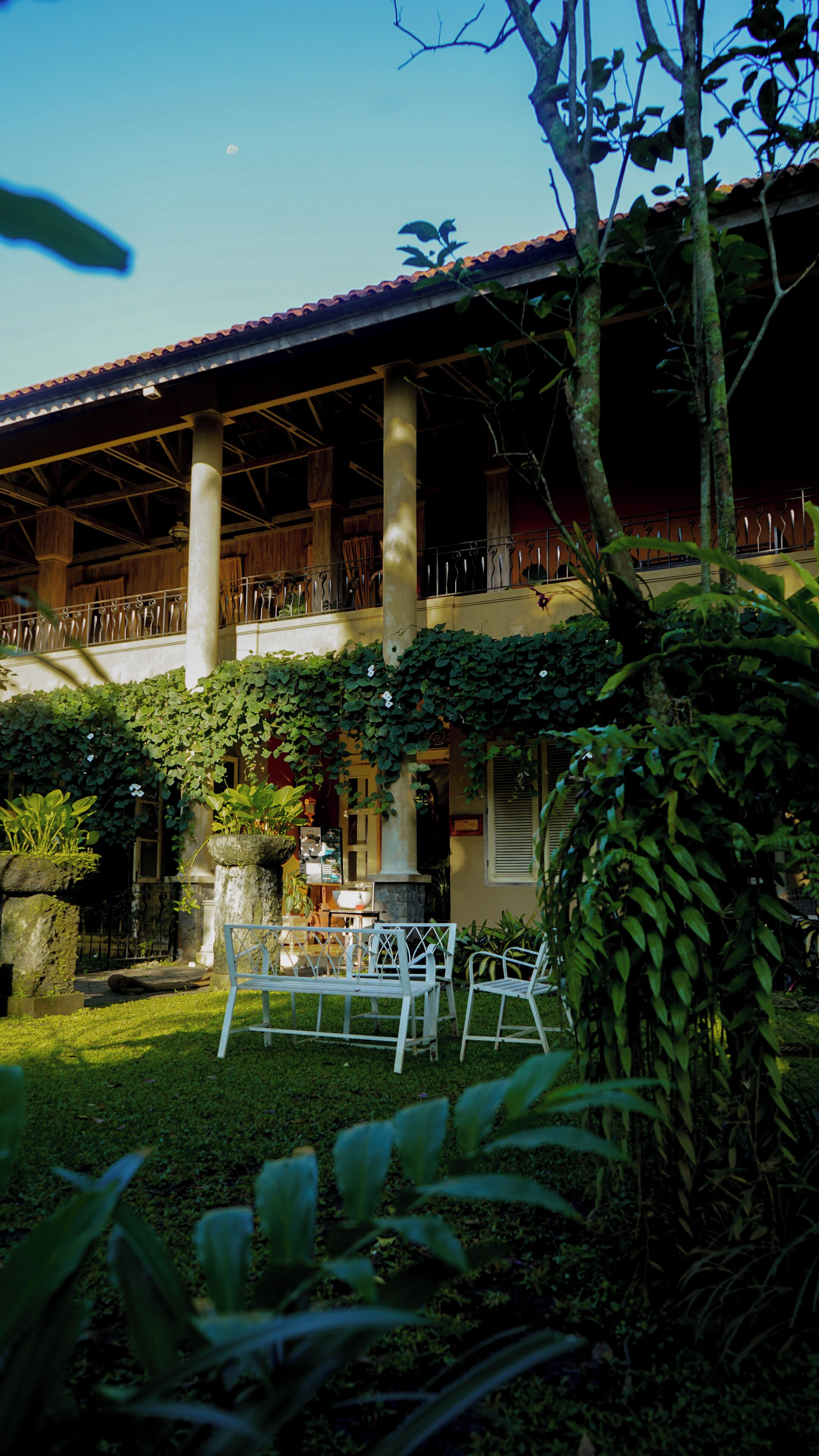 A two-story building with a covered patio area, columns, and a balcony.