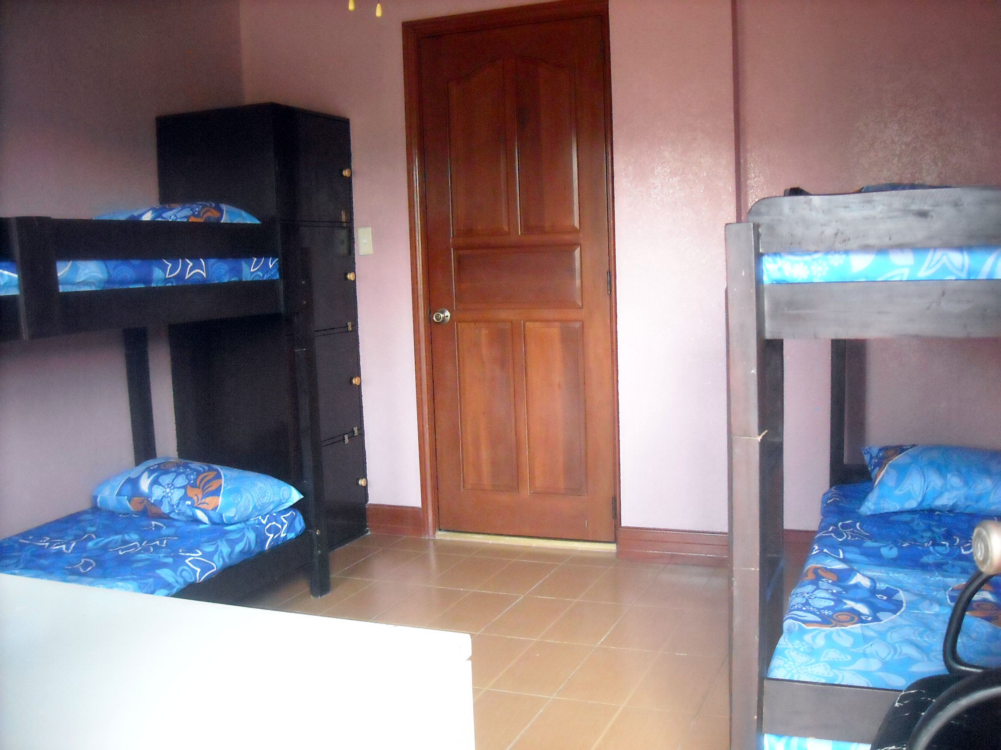 A room with bunk beds, a wardrobe, and a door.