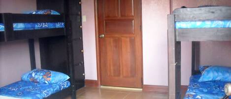 A room with bunk beds, a wardrobe, and a door.