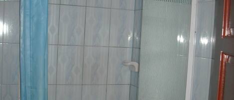 A bathroom with a shower, tiled walls, and a door with a brass handle.