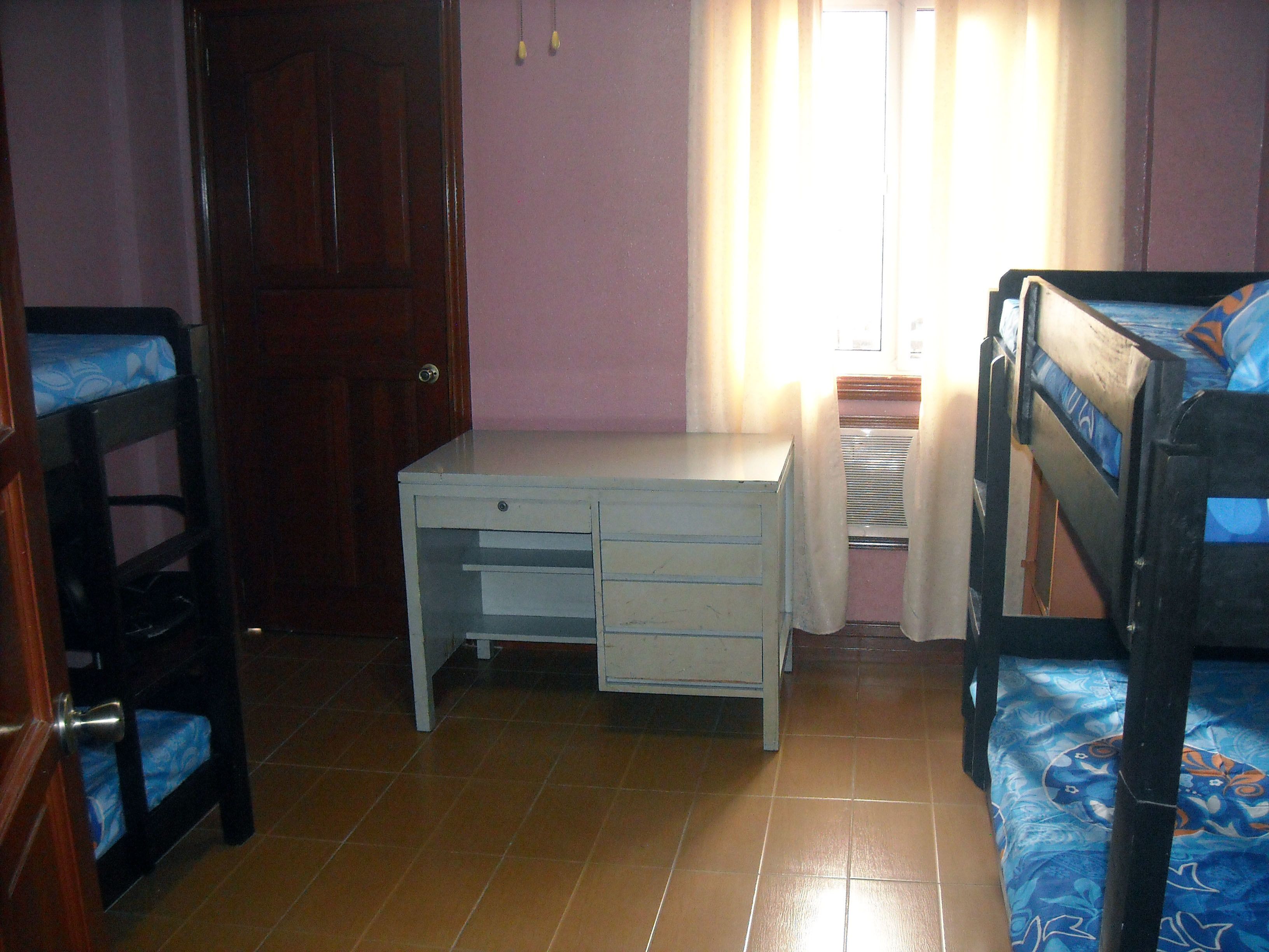 A bedroom with a bunk bed, a desk, and a chair.