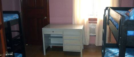 A bedroom with a bunk bed, a desk, and a chair.